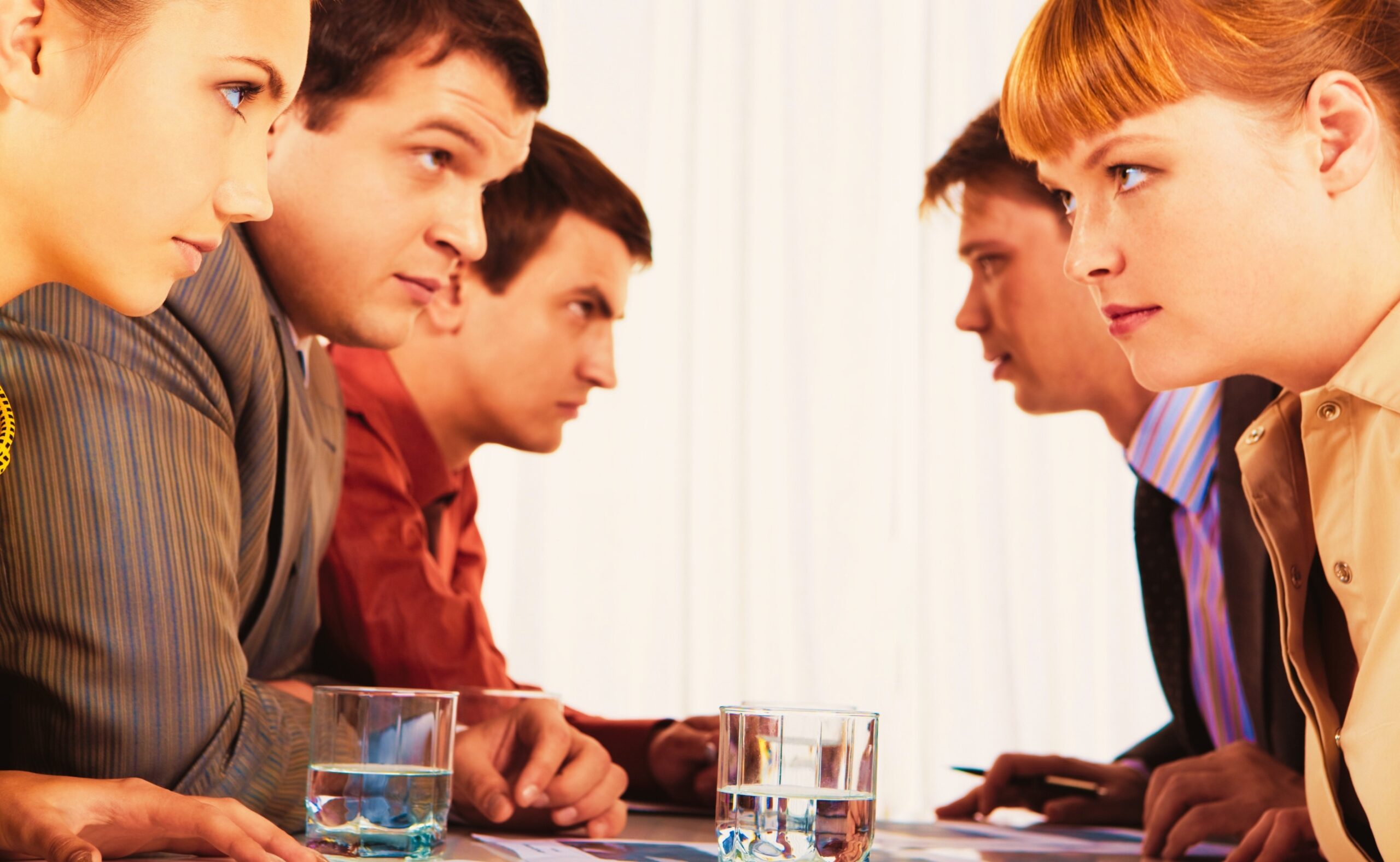 profiles of serious employees sitting in two rows and looking at each other