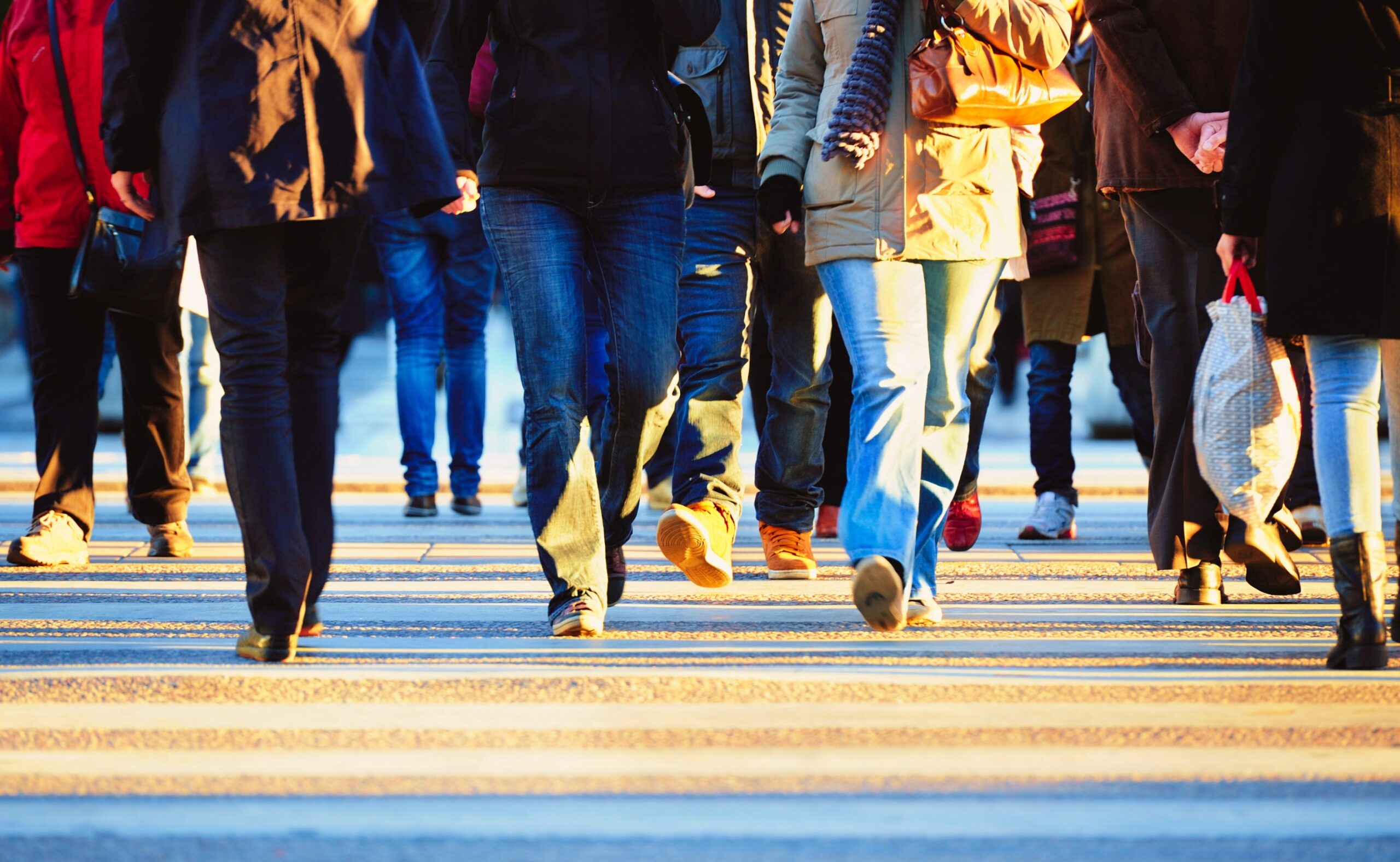 Zebra crossing with motion blurred crowd brightly lit by low sun