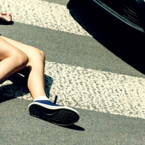 Victim of a traffic accident on pedestrian crossing next to a car