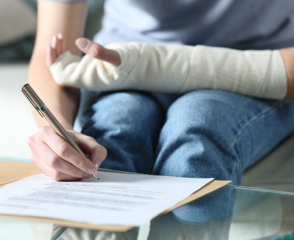 A woman writing on a paper with a cast on the left hand