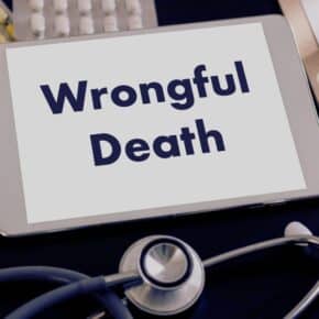 wrongful death spelled on a tablet with medicines and stethoscope on the background. concept of wrongful death settlement
