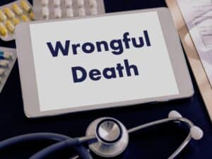 wrongful death spelled on a tablet with medicines and stethoscope on the background. concept of wrongful death settlement