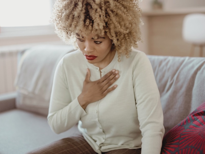 African American woman feeling sick and holding her chest in pain. Concept of Can You Get Legionnaires' Disease from Drinking Water