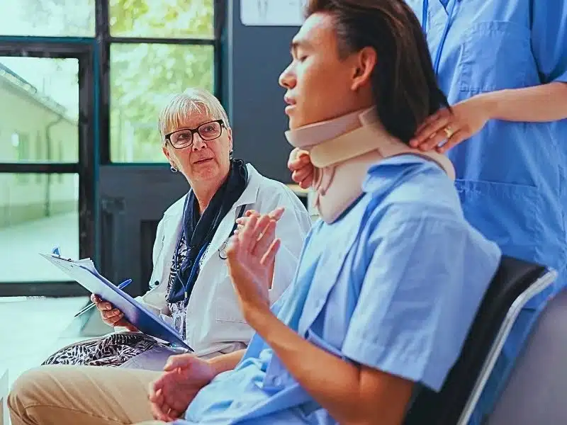 Traumatologist senior doctor and nurse helping asian patient to take off cervical neck collar during check up visit. Why workers' compensation is important