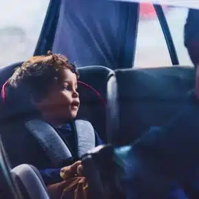 Little boy sitting in a car seat while his father drives.