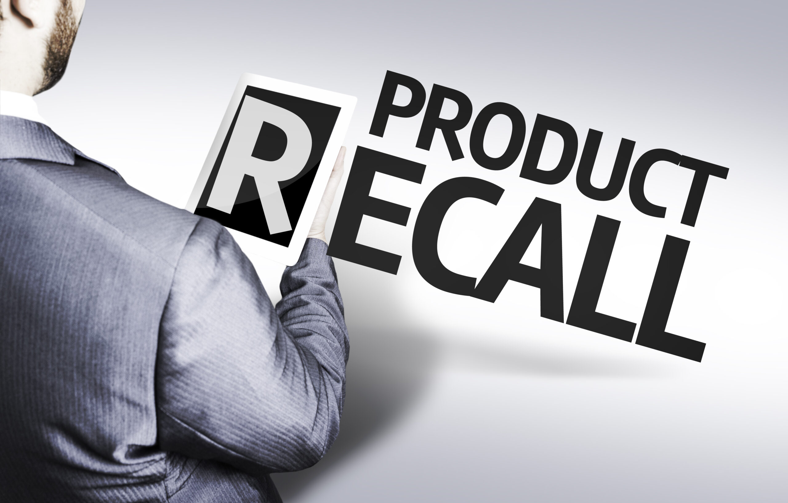 Product recall with a man in suit holding the letter "R" on a tablet device.