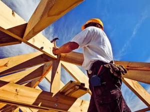 Carpenter working on roof structure at construction site.
