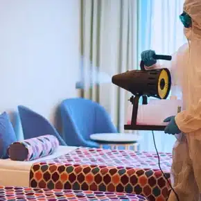 Man in protective suit disinfecting the Hotel room. Hotel room hazards