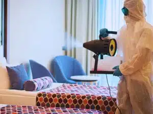 Man in protective suit disinfecting the Hotel room. Hotel room hazards