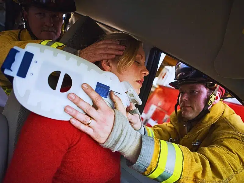 Two firemen helping woman with neck brace. Injured in a Las Vegas Car Accident While Visiting