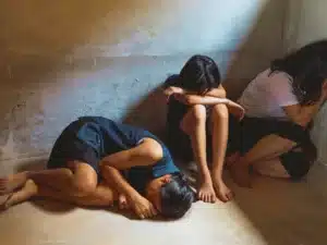 Three girls huddled together on the floor looking distressed. Trafficking Victims Protection Reauthorization Act