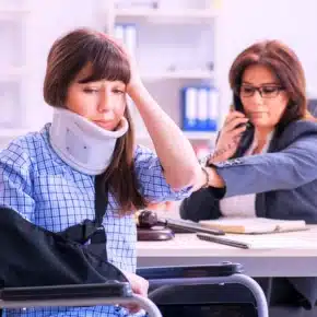 An injured woman in a neck brace sits near a lawyer. prove a slip and fall case