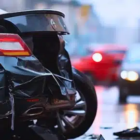 Damaged rear end of a dark car involved in collision.
